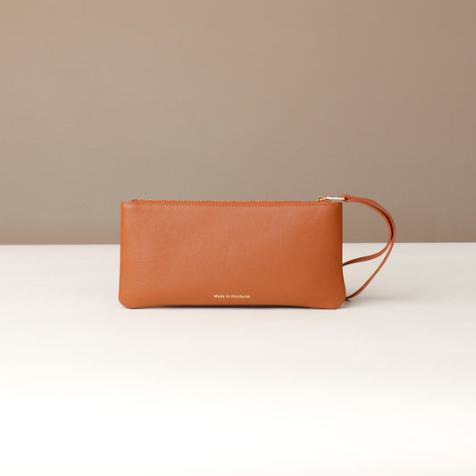 Brown leather clutch bag on a white surface with a beige background