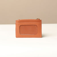 back view of a pebble leather card case nirua in light brown brown with gold accents over a beige background