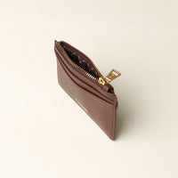 upper view of a open pebble leather card case nirua in brown with gold accents over a beige background