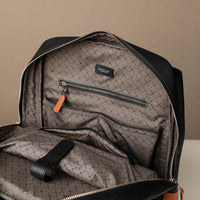 Black textured backpack with a zipper pocket on a beige background