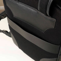 Close-up of a black backpack with a shoulder strap on a light background