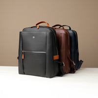 Three backpacks, one black, one brown and blue, on a beige background