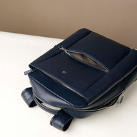 Navy blue backpack on a white surface with a beige background