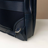 Navy blue backpack with a strap on a light beige background