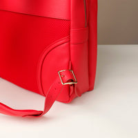 Red leather bag with a gold buckle on a light beige background