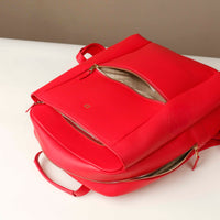Red backpack on a white surface with a neutral background