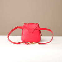 Red leather bag with a strap on a beige background