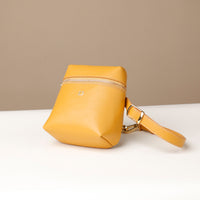 Yellow handbag with a strap on a white surface and beige background
