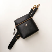 Black leather bag with gold zipper and strap on a white background