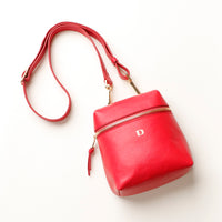 Red leather handbag with a gold zipper on a white background