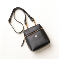 Black handbag with gold zipper and handle on a white background