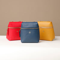 Three bags in red, blue, and yellow on a white surface with a beige background