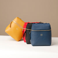 Four handbags in yellow, red, black, and blue on a beige background