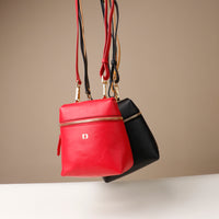 Red and black handbags with gold zippers on a beige background