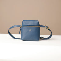 Blue leather crossbody bag on a white surface with a beige background