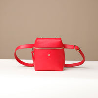 Red leather crossbody bag with gold zipper on a beige background