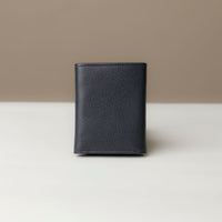 A trifold wallet in dark blue color, made from pebbled leather, displayed against a neutral background. Closed view.