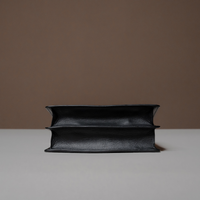 Black Nelda Bag elegant leather handbag with detachable shoulder strap with a brown background