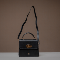 Black Nelda Bag elegant leather handbag with detachable shoulder strap on a brown background