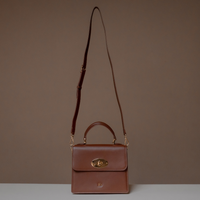Brown Nelda Bag elegant leather handbag with detachable shoulder strap on a brown background