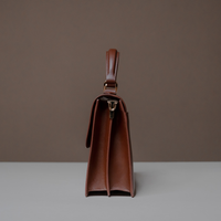 Side View of Brown Nelda Bag elegant leather handbag with detachable shoulder strap on a neutral background
