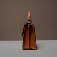Side View of Brown Nelda Bag elegant leather handbag with detachable shoulder strap on a neutral background