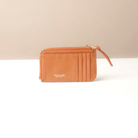 Light Brown leather card case wallet with a zipper on a beige background