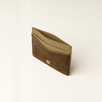 green uede leather cardholder with gold danilos logo on a beige background