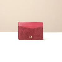 red uede leather cardholder with a gold Danilos logo on a beige background