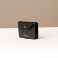 Black wallet with 'DANIELS' branding on a beige background