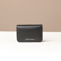 Black leather wallet with 'Made in Honduras' text on a beige background