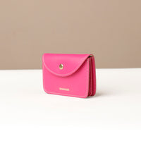 Pink wallet with gold button on a beige background