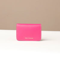 Pink wallet with 'Made in Honduras' text on a beige background