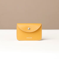 Yellow wallet with 'DANILOS' branding on a beige background