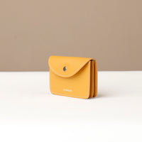 Yellow wallet with a brand name on a white surface and beige background