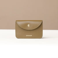 Green leather wallet with 'DANILOS' branding on a beige background