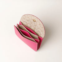 Pink wallet with beige interior on a light gray background