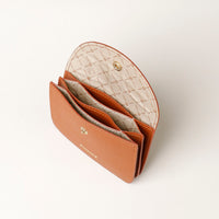Open tan leather wallet with quilted interior on a light gray background