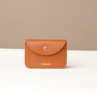 Brown leather wallet with 'DANILOS' branding on a beige background