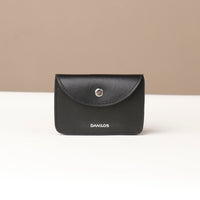 Black wallet with 'DANILOS' branding on a beige background