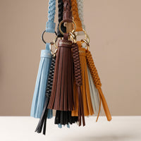 A collection of leather tassel charms in various colors attached to a black handbag.