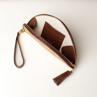 An open Clutch Agnes Raffia Panna with brown leather details, with three slots for cards, gold hardware, upper view