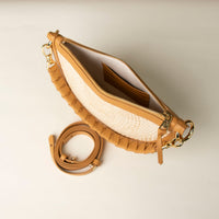 Tan leather handbag with a strap on a light background