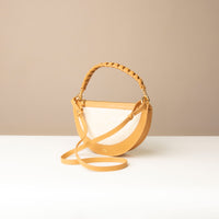 Beige handbag with twisted handle on a neutral background