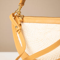 Close-up of a beige handbag with a textured strap and gold clasp.