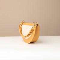 Tan handbag with white woven strap on a neutral background