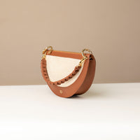 Half-moon shaped handbag with brown and beige colors on a neutral background.
