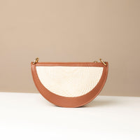 Semi-circular handbag with textured white front and brown sides on a neutral background