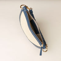 Blue and beige pouch with gold zipper and hardware on a light background