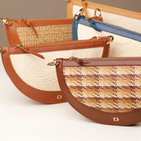 Five woven handbags with brown leather accents on a light background